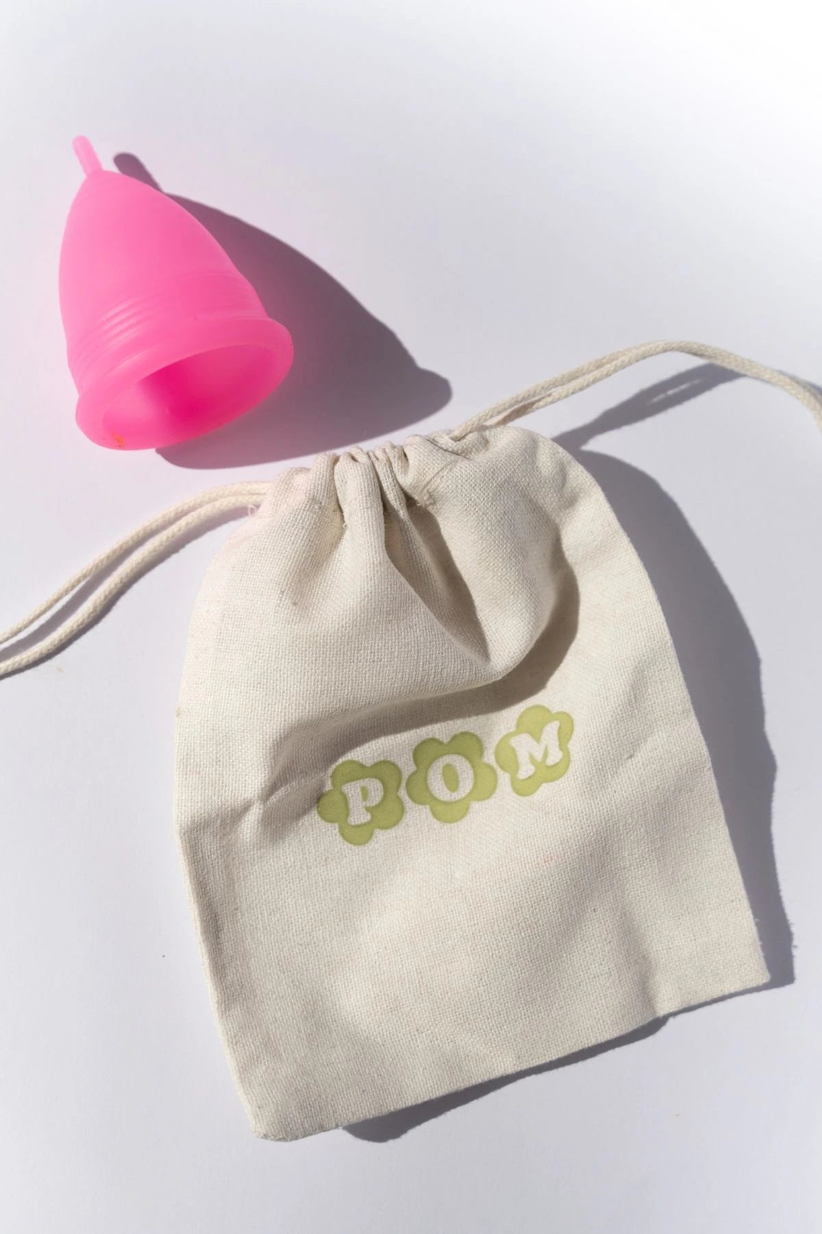 POM Super Soft Menstrual Cup in hot pink, made from 100% medical-grade silicone, shown with its organic cotton travel pouch.