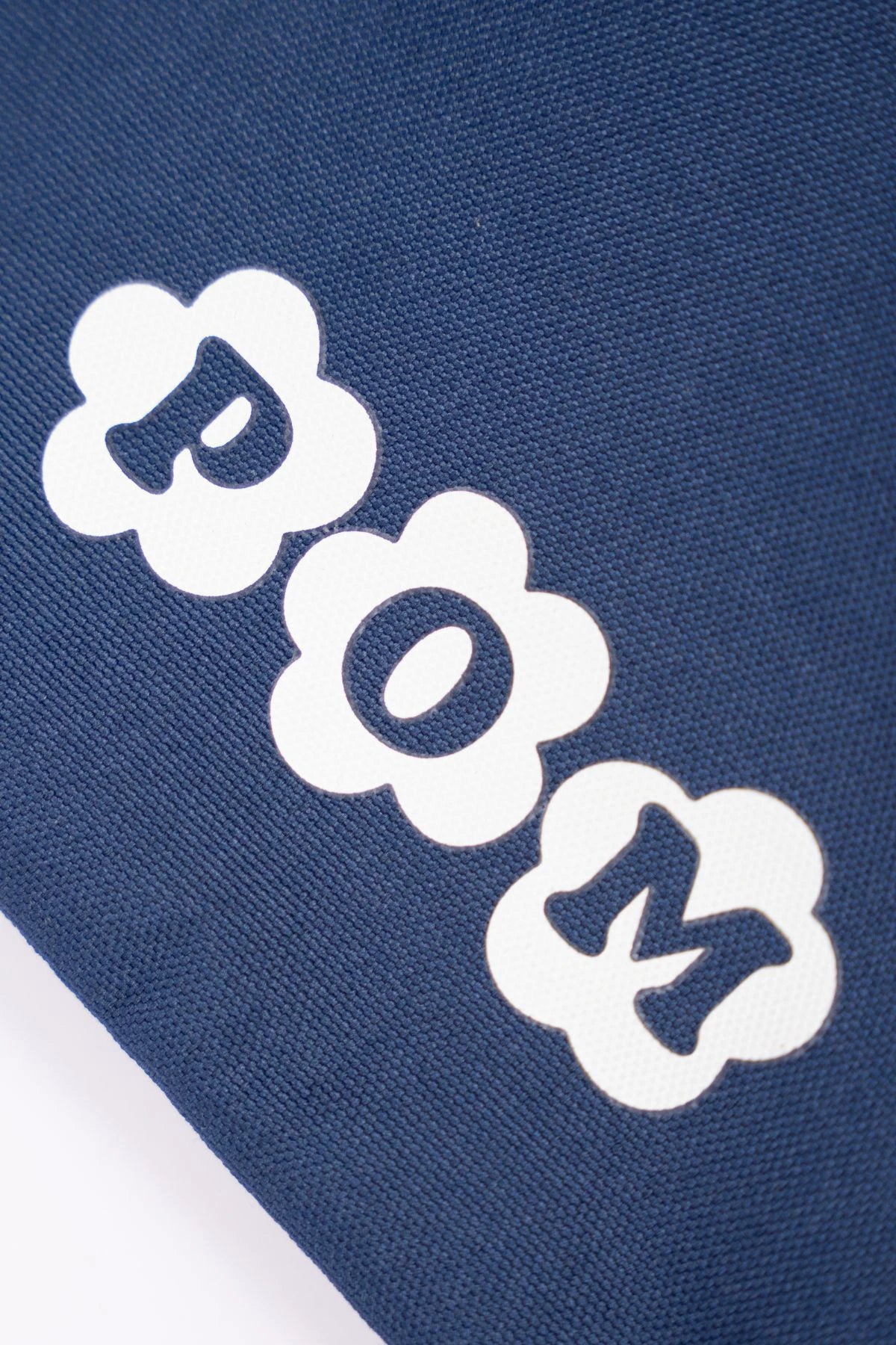 Close-up of the POM logo printed in white on the navy POM Waterproof Toiletry Bag, made from rPET (recycled plastic bottles).